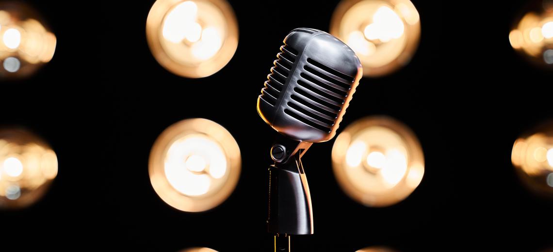 Silver microphone on stage in illuminated studio. © Freepik