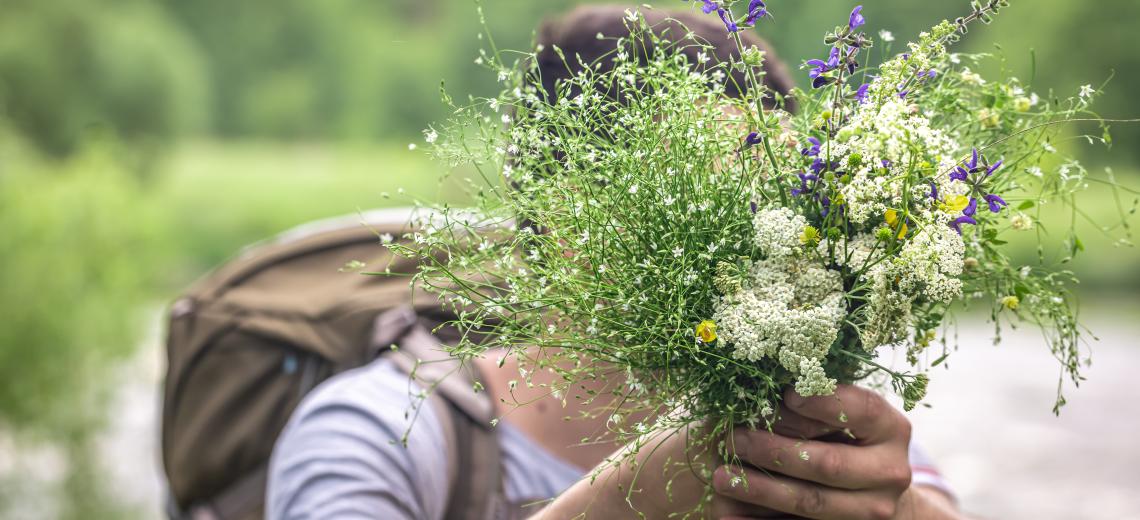Close-up of a bouquet of wildflowers in the hands of a male traveler. © freepik