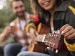 smiley-couple-playing-guitar-outdoors-while-camping © Freepik