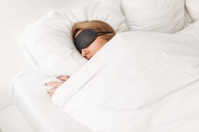 Lady wearing black eyes mask while sleeping in bed at home © magnific